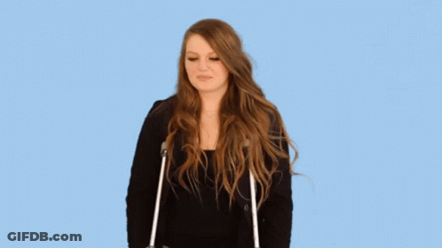 A Woman With Long Hair Is Standing With Crutches And Making A Funny Face . GIF