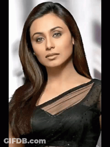 A Woman With Long Hair Is Wearing A Black Blouse And Looking At The Camera . GIF