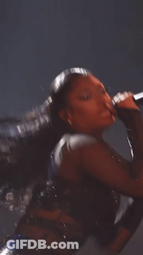 A Woman With Long Hair Is Wearing A Black Bodysuit With Rhinestones . GIF