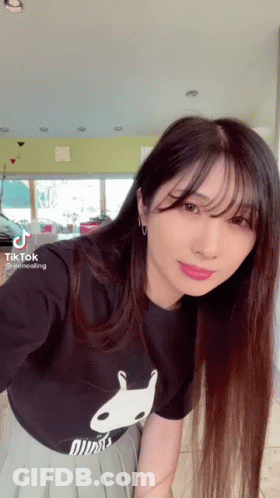 A Woman With Long Hair Is Wearing A Black T-Shirt With A White Rabbit On It . GIF