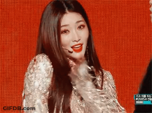 A Woman With Long Hair Is Wearing A Sequined Dress And A Microphone On A Stage . GIF