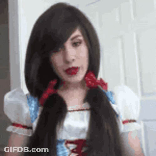 A Woman With Long Hair Is Wearing A Snow White Costume And Has A Red Bow In Her Hair . GIF
