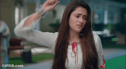 A Woman With Long Hair Is Wearing A White Shirt And Bracelets And Is Making A Funny Face . GIF