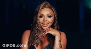 A Woman With Long Nails Is Standing In A Dark Room . GIF