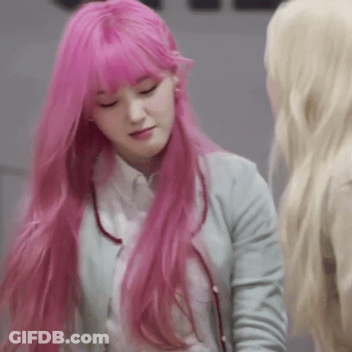 A Woman With Long Pink Hair And Bangs Is Standing Next To Another Woman . GIF