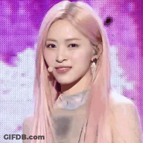 A Woman With Long Pink Hair Is Standing In Front Of A Purple Background . GIF
