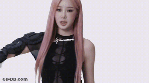 A Woman With Long Pink Hair Is Wearing A Black Tank Top And A Black Arm Protector . GIF
