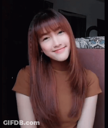 A Woman With Long Red Hair And Bangs Is Smiling For The Camera GIF