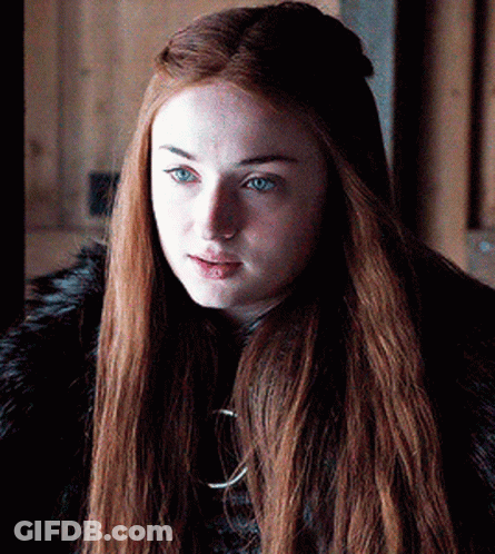 A Woman With Long Red Hair And Blue Eyes Is Wearing A Black Fur Coat . GIF