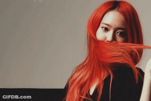 A Woman With Long Red Hair Is Covering Her Face With Her Hair GIF