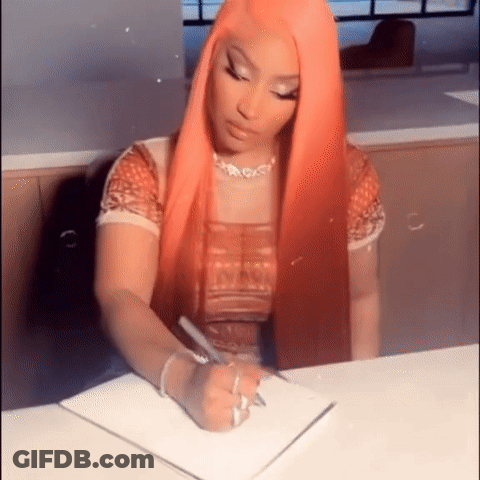 A Woman With Long Red Hair Is Sitting At A Table Writing In A Notebook . GIF