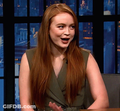 A Woman With Long Red Hair Is Sitting In Front Of A Window GIF