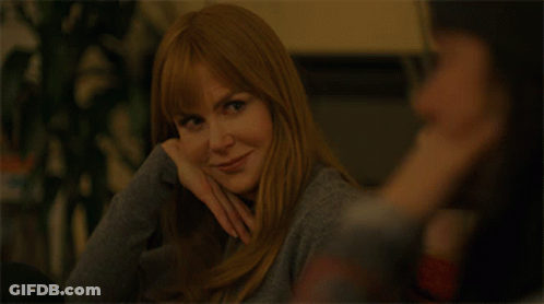 A Woman With Long Red Hair Is Smiling And Looking At The Camera GIF