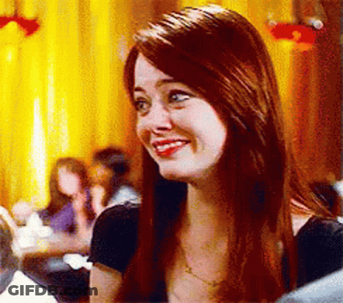 A Woman With Long Red Hair Is Smiling While Sitting In A Restaurant . GIF