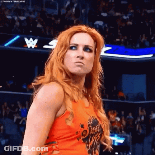 A Woman With Long Red Hair Is Standing In Front Of A Crowd In A Wrestling Ring . GIF