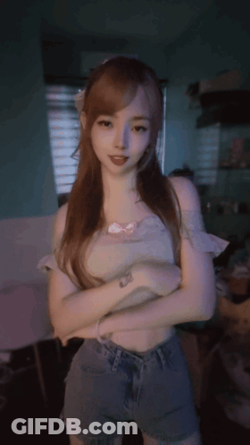 A Woman With Long Red Hair Is Standing With Her Arms Crossed In A Dark Room GIF