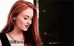 A Woman With Long Red Hair Is Wearing A Black Dress And A Necklace . GIF