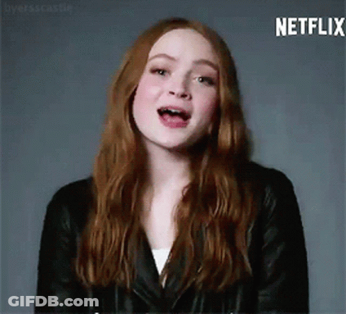 A Woman With Long Red Hair Is Wearing A Black Leather Jacket And A White Shirt . GIF