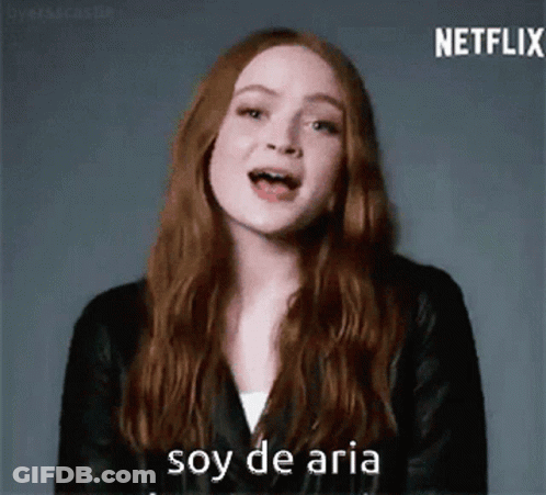 A Woman With Long Red Hair Is Wearing A Black Leather Jacket And Says Soy De Aria . GIF