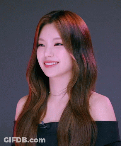 A Woman With Long Red Hair Is Wearing A Black Off The Shoulder Top And A Necklace GIF