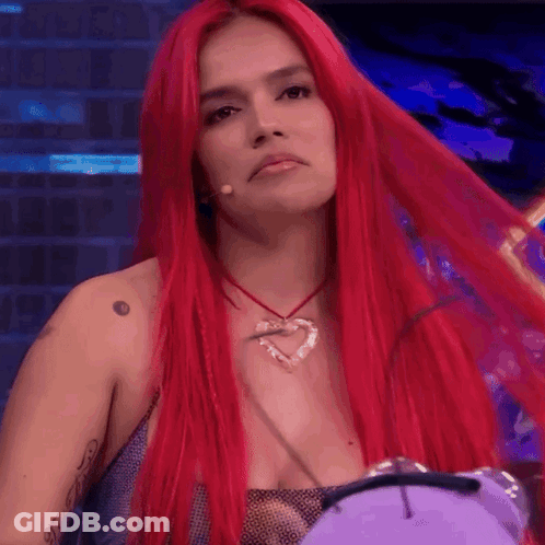 A Woman With Long Red Hair Is Wearing A Heart Necklace GIF