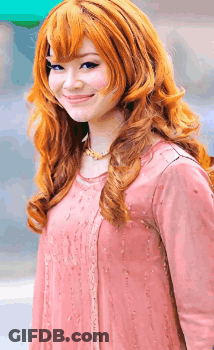 A Woman With Long Red Hair Is Wearing A Pink Top GIF