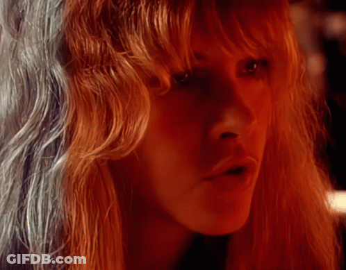 A Woman With Long Red Hair Looks At The Camera GIF