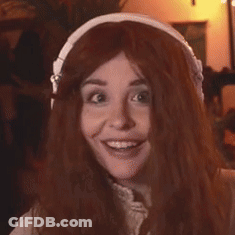 A Woman With Long Red Hair Wearing Headphones And Smiling . GIF