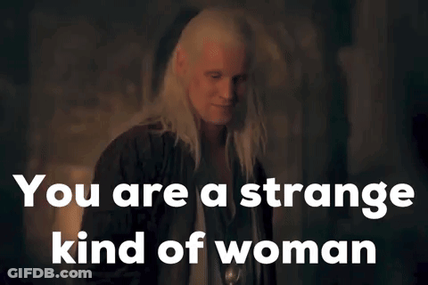 A Woman With Long White Hair Is Standing In A Dark Room With The Words `` You Are A Strange Kind Of Woman '' Above Her . GIF