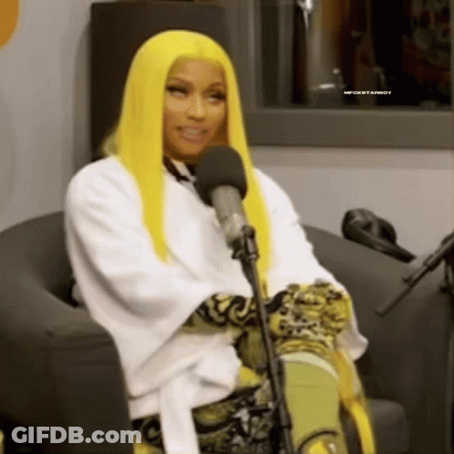 A Woman With Long Yellow Hair Is Sitting In Front Of A Microphone . GIF