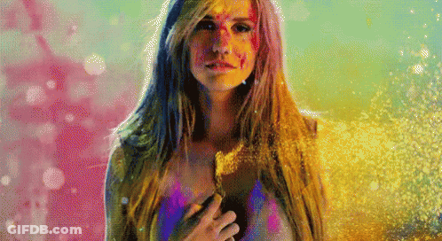 A Woman With Paint On Her Face Is Standing In Front Of A Pink And Blue Background GIF