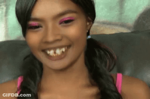 A Woman With Pigtails And Pink Eye Shadow Smiles GIF