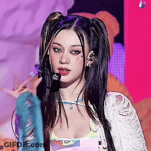A Woman With Pigtails Is Singing Into A Microphone On A Stage GIF