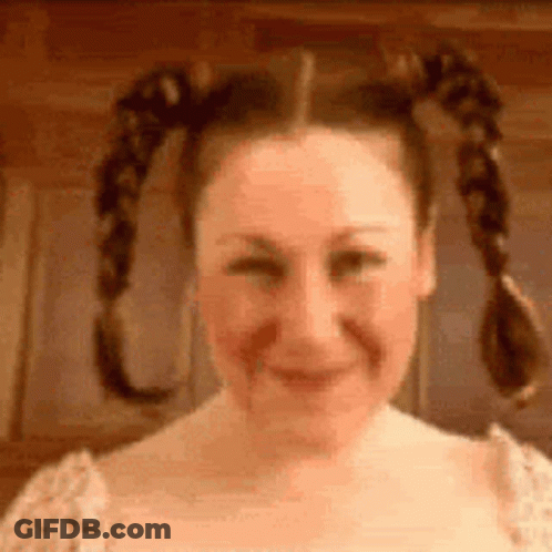 A Woman With Pigtails Is Smiling And Making A Face . GIF