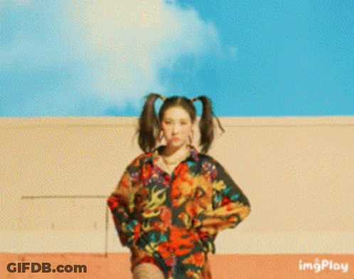 A Woman With Pigtails Is Standing In Front Of A Building With Imgplay Written On The Bottom Right GIF