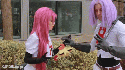 A Woman With Pink Hair And A Man With Purple Hair Are Holding A Toy GIF