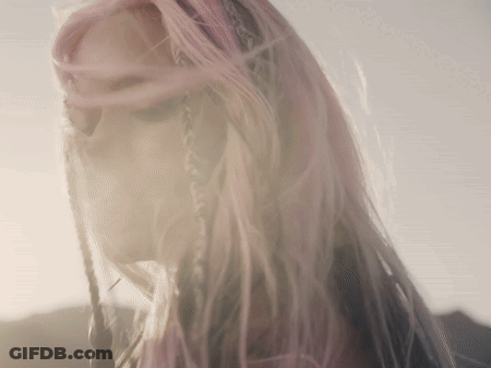 A Woman With Pink Hair And Braids Looks Down GIF