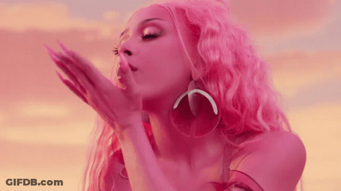 A Woman With Pink Hair And Earrings Blowing A Kiss GIF