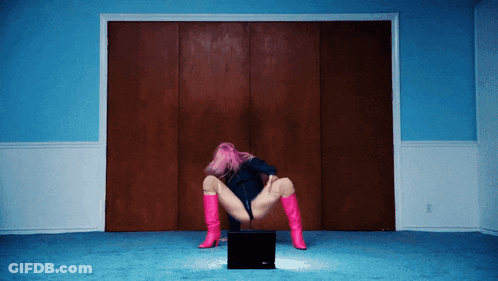 A Woman With Pink Hair And Pink Boots Is Kneeling On A Laptop GIF