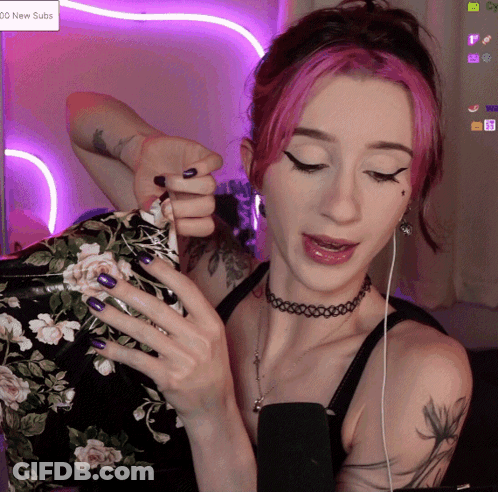 A Woman With Pink Hair And Purple Nails Is Playing A Game On A Screen That Says 100 New Subs GIF