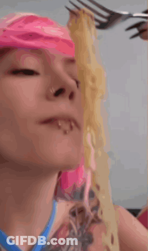 A Woman With Pink Hair Eats Noodles With A Fork GIF