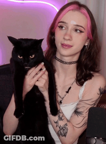 A Woman With Pink Hair Holds A Black Cat In Her Arms GIF