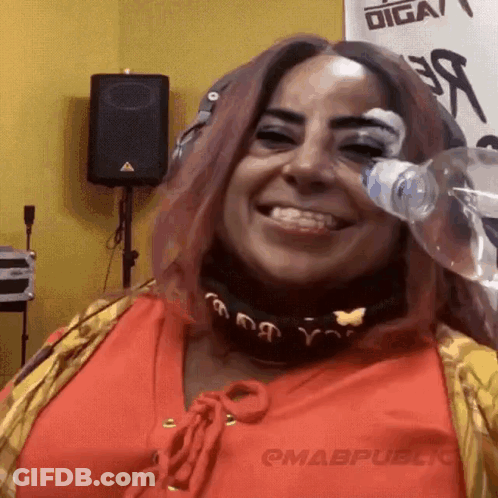 A Woman With Pink Hair Is Drinking From A Bottle Of Water GIF