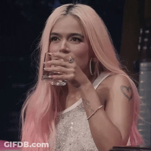 A Woman With Pink Hair Is Drinking From A Clear Glass GIF