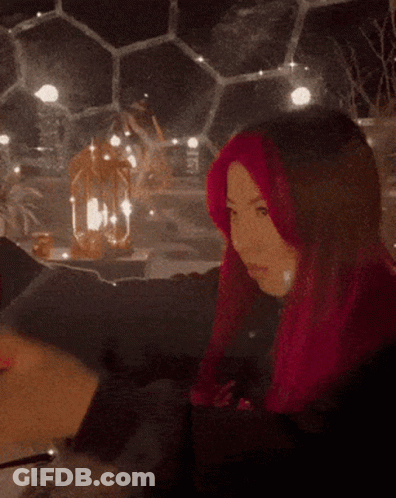 A Woman With Pink Hair Is Holding A Glass Of Water GIF