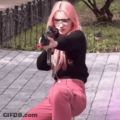 A Woman With Pink Hair Is Holding A Gun In Her Hand While Wearing Safety Glasses . GIF