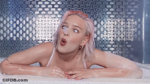 A Woman With Pink Hair Is In A Bathtub GIF