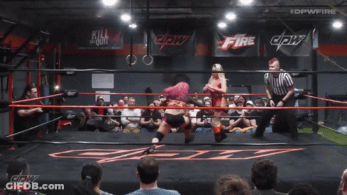 A Woman With Pink Hair Is In A Wrestling Ring With #Dpwfire Written Above Her GIF