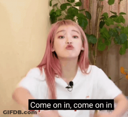 A Woman With Pink Hair Is Making A Funny Face And Says Come On In Come On In GIF
