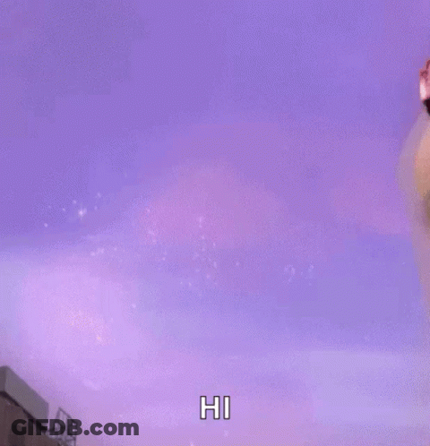 A Woman With Pink Hair Is Saying Hi In Front Of A Purple Background GIF